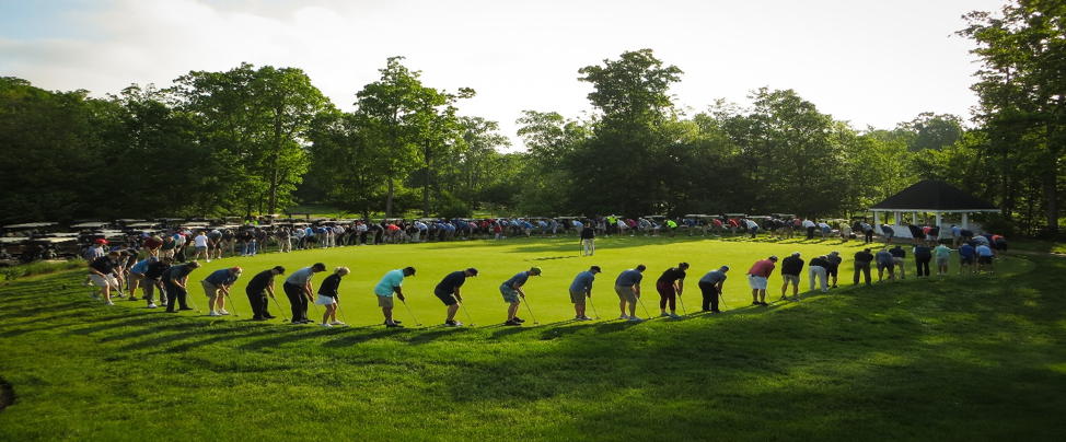 Participants of the Govplace 2019 Charity Golf Tournament in a circle trying to get the ball in one hole in the center.